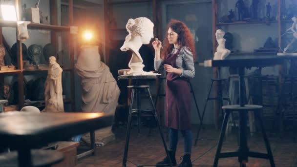 En dam borstar en gipsbyst i en studio. Inspiration, kreativitet, design, fantasi koncept. — Stockvideo