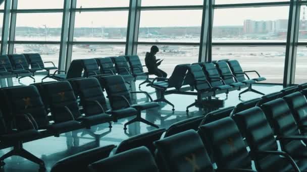 Empty airport with a boy playing with his tablet. Airport terminal. Pandemic, covid-19 lockdown concept. — Stock Video