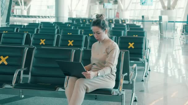 Empty departure lounge with a woman typing on her laptop — Stock Video