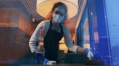 Bir garson ve bir garson bir kafede masaları siliyor.