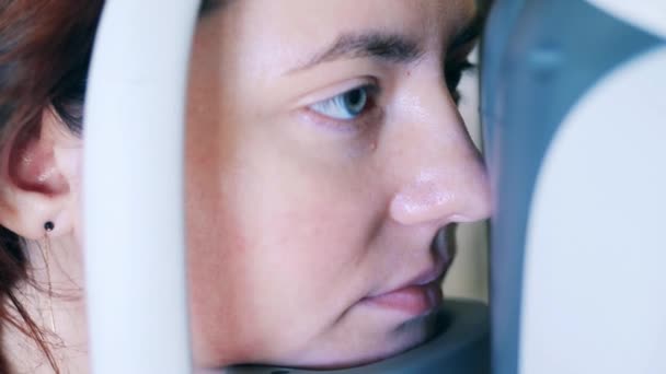 Een dame laat haar gezichtsvermogen onderzoeken door een medisch mechanisme. — Stockvideo