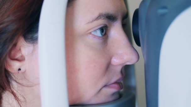 Una mujer está mirando un dispositivo médico que examina su vista. — Vídeo de stock