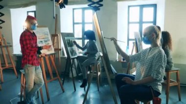 Resim dersi veren maskeli bir öğretmenle sanat okulunda.