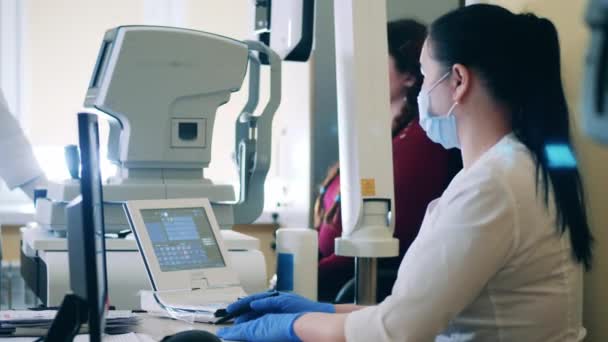 Arzt betreibt einen medizinischen Komplex, um die Augen von Frauen zu untersuchen — Stockvideo