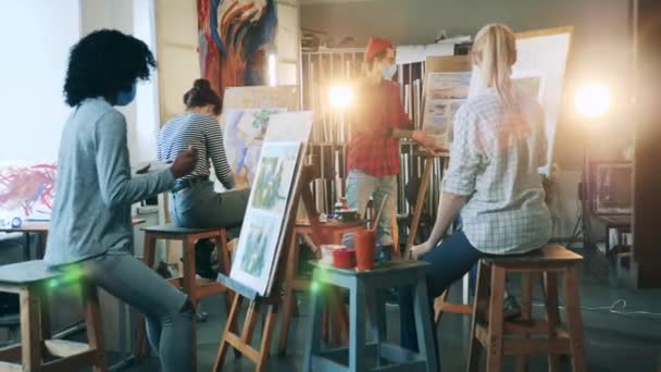 Un uomo in maschera sta insegnando pittura in studio. Lezione d'arte con gli studenti. — Video Stock