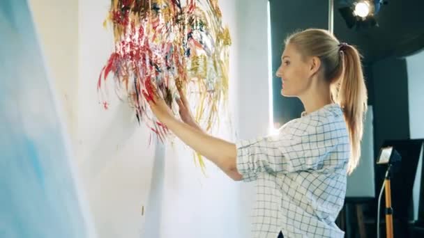 Lady artist is smearing paint with her hands — Stock Video