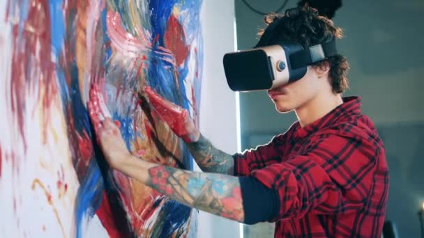 Ein Künstler mit VR-Brille malt ein buntes Bild. Virtuelle Realität, futuristisches Kunstkonzept. — Stockvideo