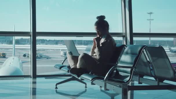 Uma senhora está trabalhando em seu laptop enquanto espera por seu voo — Vídeo de Stock