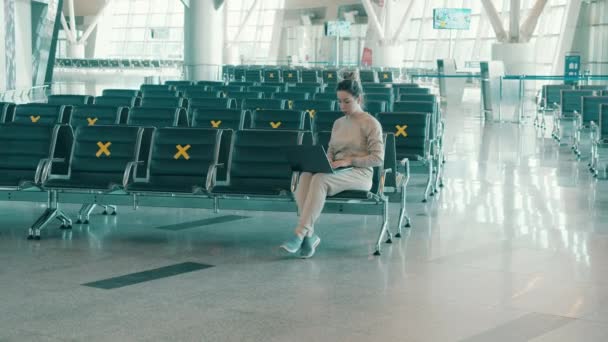 Salão de aeroporto vazio com uma mulher trabalhando em seu laptop — Vídeo de Stock