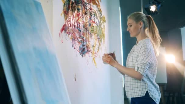 Blond lady is cheerfully painting an abstract picture — Stock Video