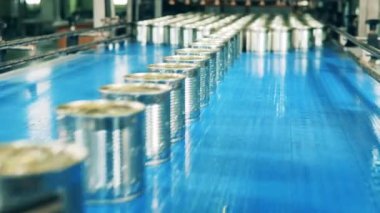 Mühürlü teneke kutuların mekanik olarak taşınması. Fabrika taşıyıcısı, metal kutularla endüstriyel üretim hattı..