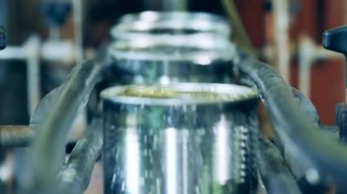 Fabrika taşıyıcısı, metal kutularla endüstriyel üretim hattı. Mühürlenmemiş teneke kutular konveyör boyunca sıra sıra ilerliyor.