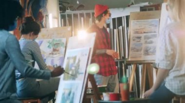 Resim dersi sırasında bir grup resim öğrencisi erkek bir öğretmen tarafından tutuluyor.