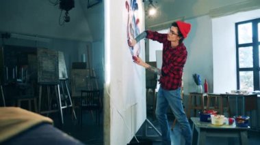 Üzerinde resim çizen bir adam olan büyük bir tuval.