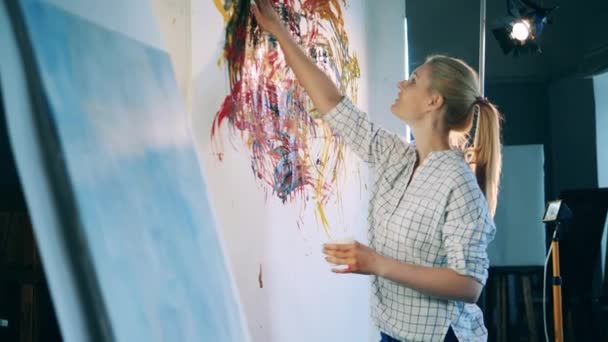 Vreugdevolle vrouw schildert met haar handen in het atelier — Stockvideo