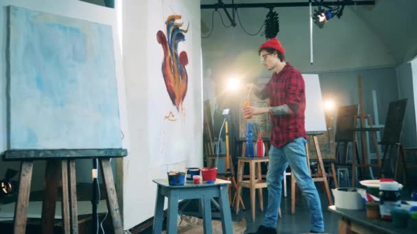 Mannelijke schilder besprenkelt een schilderij met verven — Stockvideo