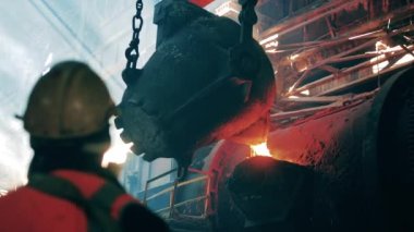 Çelik üreticisi, metalürji uzmanı, metal fabrikasında metal işçisi. Çelik işçisinin kontrolü altında erimiş metal dökülüyor.