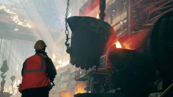 Metallurgiska fabrikskoncept. Stålarbetare observerar smält metall hälla från tanken — Stockvideo