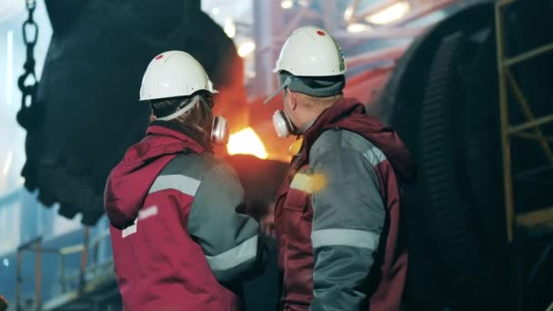 Ståltillverkare, metallurg, metallarbetare på metallfabriken. Två stålarbetare diskuterar metallurgiska processer. Koncept för metallverk. — Stockvideo