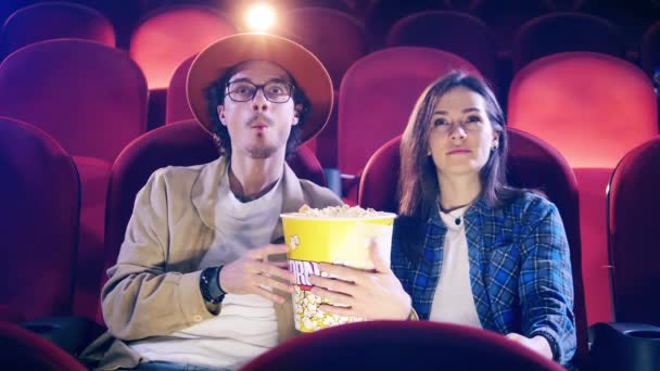 Un uomo e una donna stanno mangiando popcorn mentre guardano un film — Video Stock