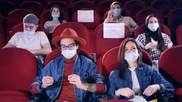 Bioscoop, film, entertainment concept. Mensen met gezichtsmaskers zetten een bril op in de bioscoop. — Stockvideo