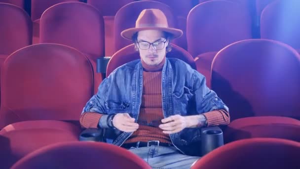 Egy férfi 3D-s szemüveget vesz fel, miközben moziban van. — Stock videók