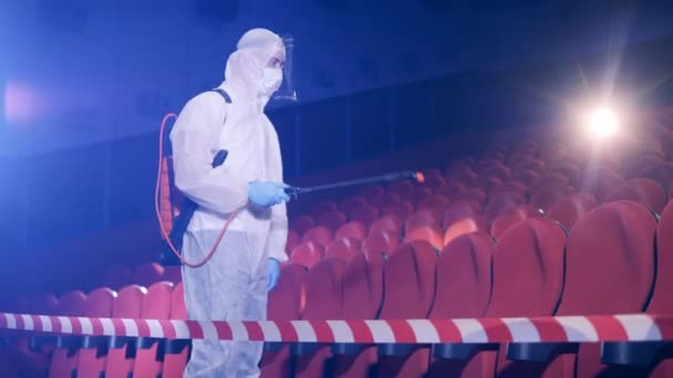 Um especialista em um terno hazmat está desinfetando uma sala de cinema — Vídeo de Stock