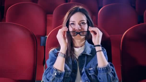 En dam sätter på sig 3D-glasögon medan hon tittar på en film — Stockvideo