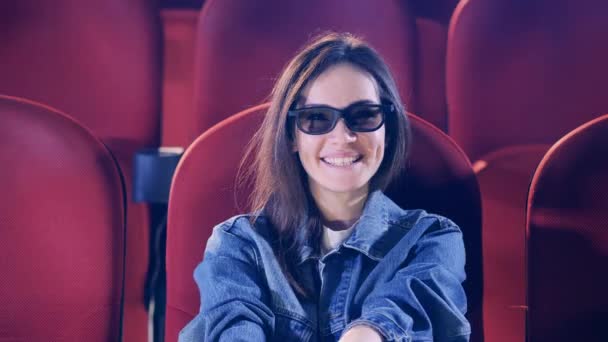 En kvinna i glasögon som ler medan hon tittar på en film — Stockvideo