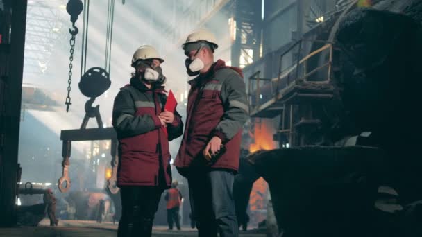 Un trabajador y una trabajadora están hablando en la fábrica metalúrgica. Concepto de fábrica metalúrgica. — Vídeo de stock