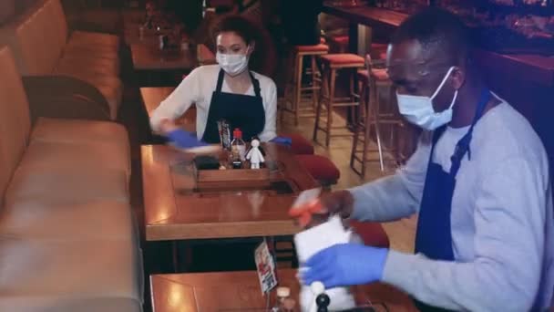Een serveerster en een ober maken het café schoon tijdens de pandemie. — Stockvideo
