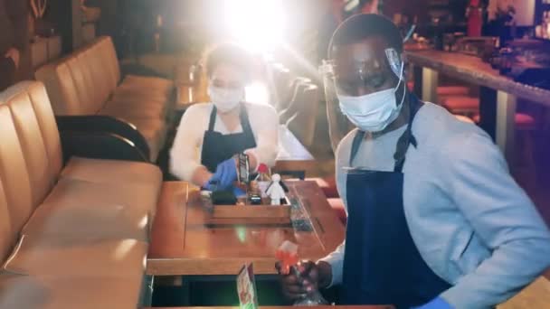 Cafe-Mitarbeiter wischen Tische ab, während sie Mundschutz tragen — Stockvideo