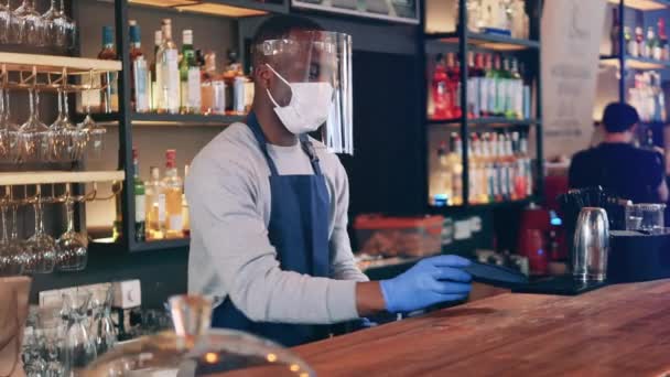 Afrikai etnikai pincér arcmaszkban elfogadja NFC fizetés a bárban — Stock videók