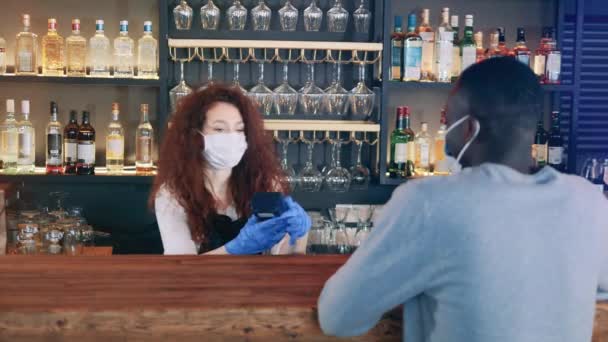 Cafékellnerin mit Gesichtsmaske akzeptiert NFC-Zahlung — Stockvideo
