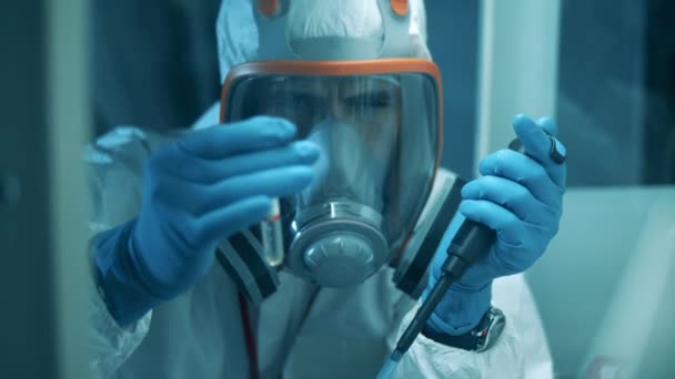 Egy vegyvédelmi ruhás férfi pipettát és csövet használ, miközben a laborban dolgozik. Covid19, koronavírus-koncepció. — Stock videók