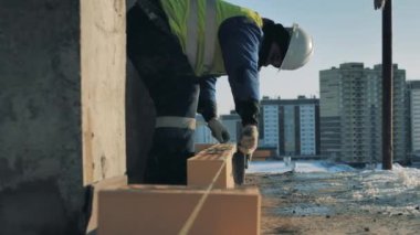 İnşaatçı tuğlalardan taze çimento temizliyor.