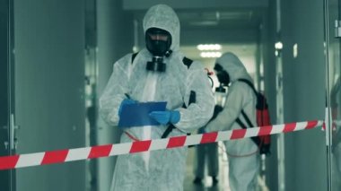 Dezenfeksiyon işçisi koridorda not alıyor. Coronavirus, covid-19 konsepti.