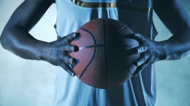 Close up de uma bola de basquete nas mãos de um jogador de etnia africana — Vídeo de Stock