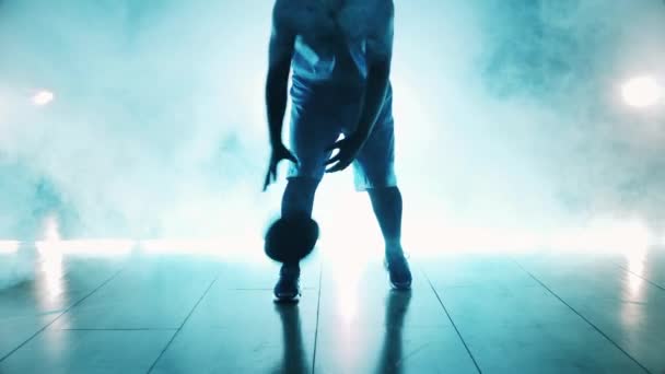 Sportsman está regateando una pelota de baloncesto en la oscuridad — Vídeos de Stock