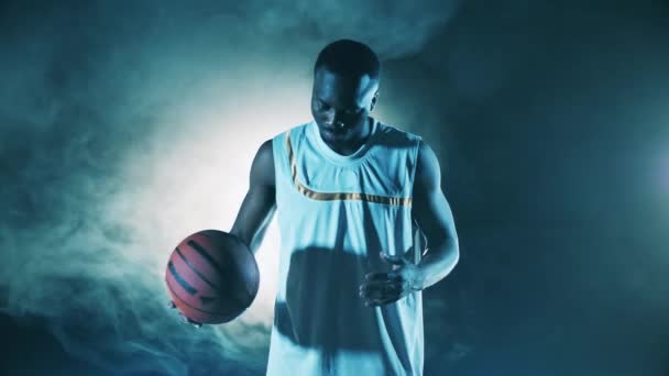 Dunkler Raum mit Rauch und einem afrikanischen Basketballspieler — Stockvideo