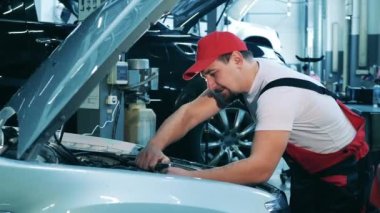 Araba tamiri ustası bir otomobili tamir etmek için İngiliz anahtarı kullanır.