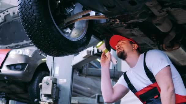 Car repair master examines a wheel with a flashlight — Stock Video