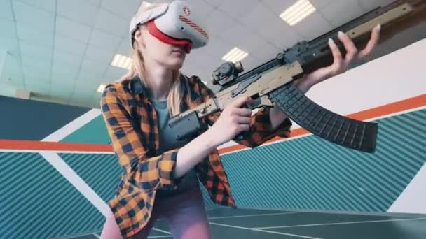 Młoda kobieta bierze udział w grze VR z fałszywą bronią. Gra VR, koncepcja rozszerzonej rzeczywistości. — Wideo stockowe