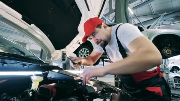 Mechanik samochodowy używający klucza do dokręcenia nakrętki. Serwis samochodowy, mechanik samochodowy. — Wideo stockowe