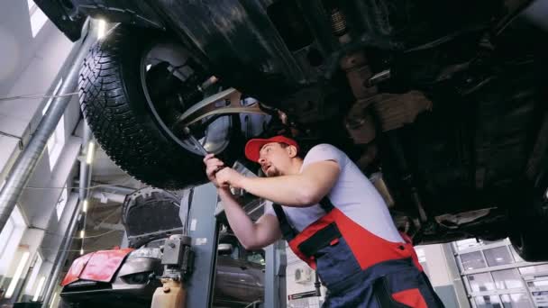 Manlig auto mekaniker drar åt ett hjul med en skiftnyckel — Stockvideo