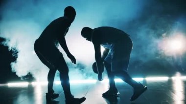 İki sporcu antrenman sırasında basketbol topu için kavga ediyor.