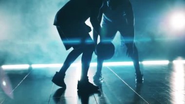Basketbol antrenmanı sırasında iki sporcu bir top için yarışıyor.