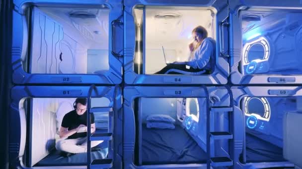 Pod hotel kapslar med ungdomar tillbringar tid i dem — Stockvideo