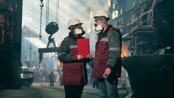 Dos trabajadores del acero en ropa de seguridad están hablando en el lugar de trabajo — Vídeo de stock