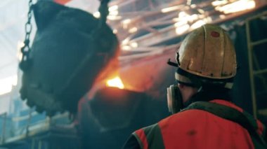 Çelik işçisi metal nakline bakıyor.